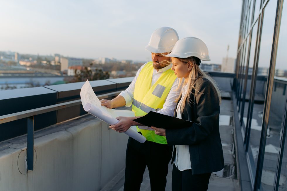 Architekt a inženýr si prohlížejí projekt na střeše postavené kanceláře.